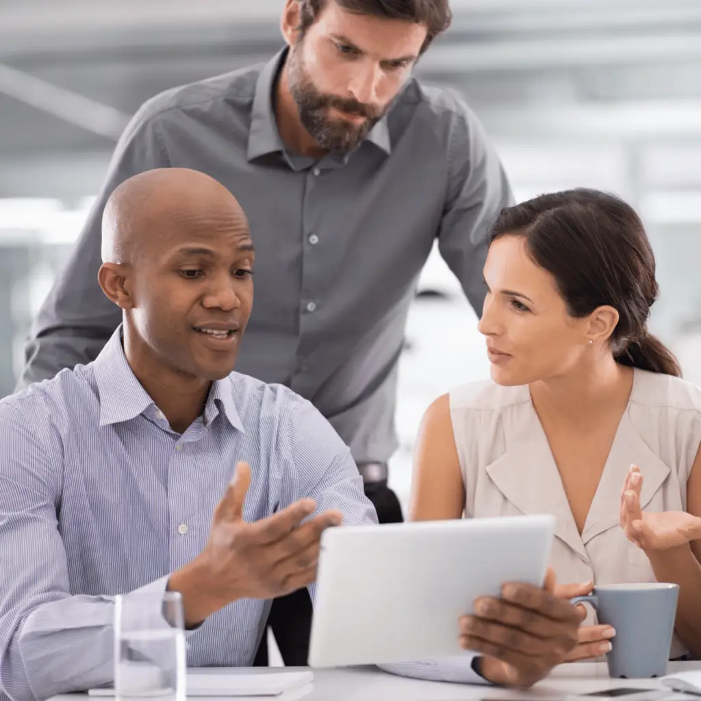 Photo of three coworkers talking and looking at a tablet